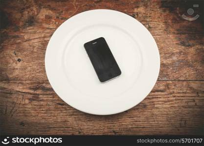 A black smart phone on a white plate