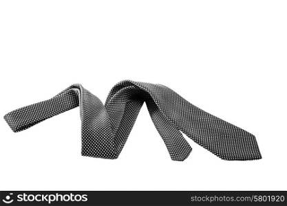 A black tie with a white dotted pattern lie on a white isolated background.