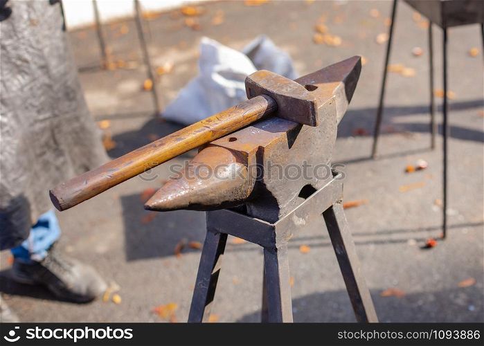 A blacksmith forges a metal blank on the anvil at a fair in the presence of spectators. Close-up.. A blacksmith forges a metal blank on the anvil at a fair in the presence of spectators.