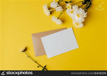 A blank card with envelope and flower is placed on yellow background
