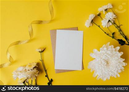 A blank card with envelope and flowers is placed on yellow background