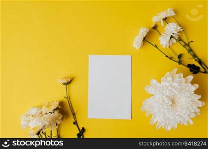 A blank card with envelope and flowers is placed on yellow background