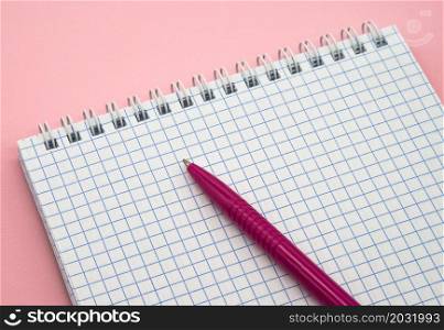 A blank checkered sheet of paper. Notepad and pen on pink. Pink Pen. Notepad spring Spiral spiral checked sheets.. Notepad and pen on pink. Pink Pen. A blank checkered sheet of paper. Notepad spring Spiral spiral checked sheets.