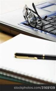 A blank notebook and glasses on laptop (focus on the glasses)