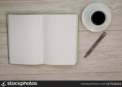 A blank notebook with a pencil and a cofee on a grey wooden background