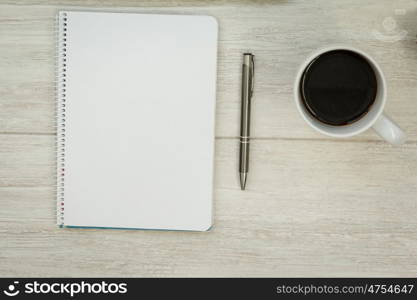 A blank notebook with a pencil and a cofee on a grey wooden background