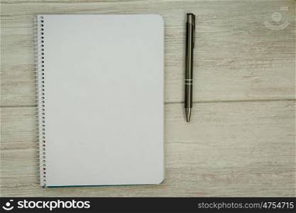 A blank notebook with a pencil and glasses on a grey wooden background