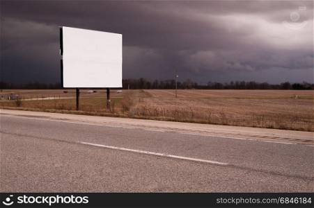 A blank white billboard with nothing on it next to the highway