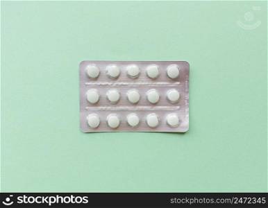 A blister of pills in the middle green background. Monochrome simple flat lay with pastel texture. Medical concept. Stock photography.. A blister of pills in the middle green background. Monochrome simple flat lay with pastel texture. Medical concept. Stock photo.