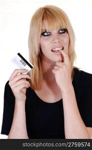 A blond pretty woman, holding a credit card in her hand, thinking ifshe should buy something or not, over white background.