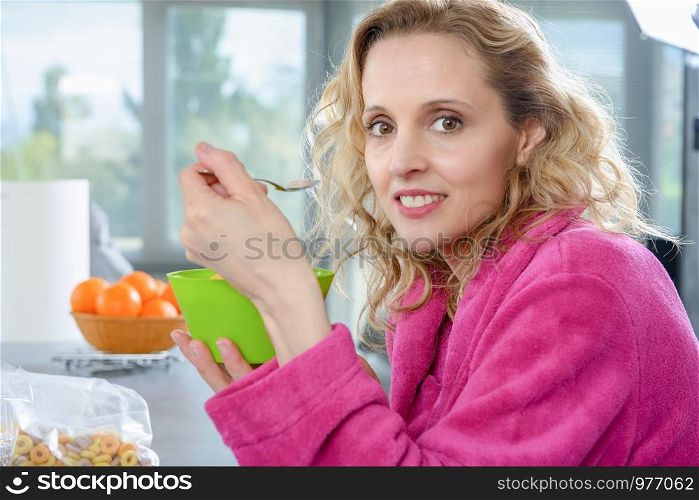 a blond woman eating cereals, at morning