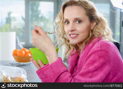 a blond woman eating cereals, at morning