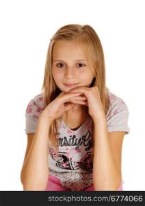 A blond young girl sitting on a chair with her hands under her chin isolatedfor white background