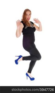 A blond young woman in black tights dancing with her hands raisedlooking into the camera, isolated for white background.