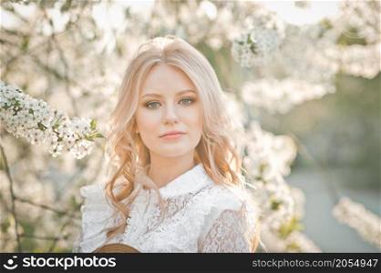 A blonde among the flowering trees in the sun.. A large portrait of a blonde among flowers 2729.