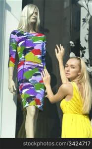 a blonde in yellow dress near the show-window and dummy