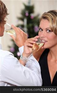 a blonde woman and a man crossing arms and toasting with sparkling wine flutes