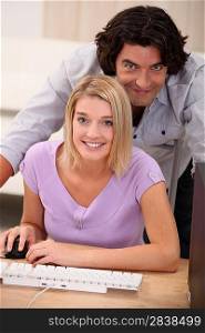 a blonde woman doing computer and her husband facing the camera