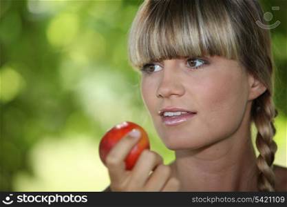 a blonde woman eating an apple