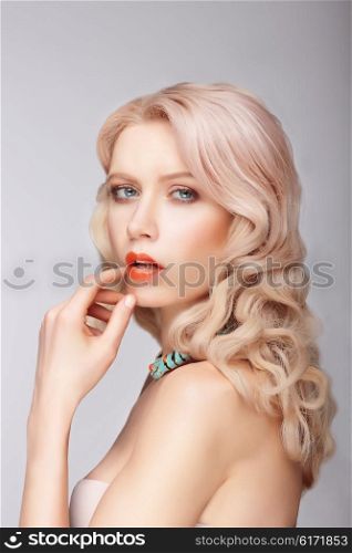 A blonde woman with a gentle makeup. Portrait. Finger touches lips.