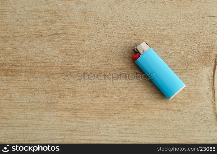 A blue lighter isolated on a wooden background
