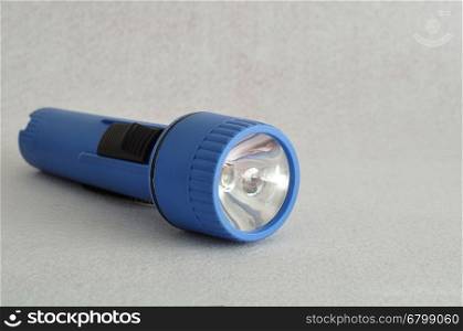 A blue plastic flashlight isolated against a white background