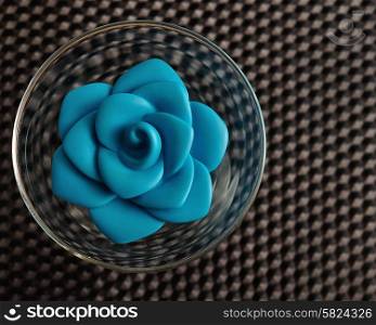 A blue plastic rose in a glass bowl used for decoration
