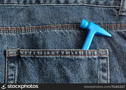 A blue toy hammer in the back pocket of a denim jean