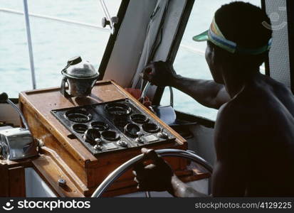 A boat captain navigates a powerboat off the shore of Jamaica