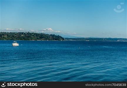 A boat is moored on the Puget Sound with Mount Rainier in the distance.