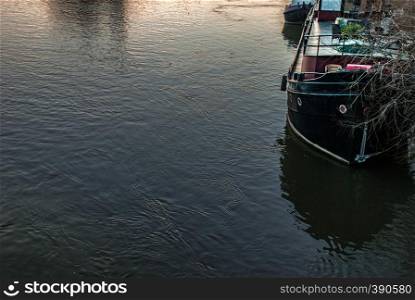 A boat that is parked on the banks of the River Thames at sunset
