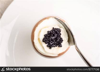A boiled egg for breakfast with mayonaise and caviar on top.