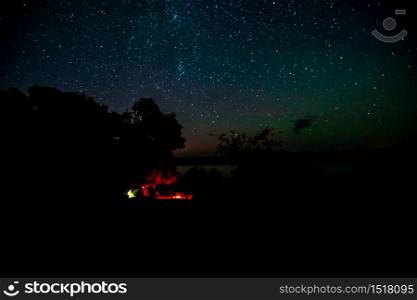 A bonfire, a lake and a starry sky over a fishing camp