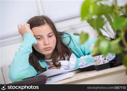 a bored teenage girl is doing her homework