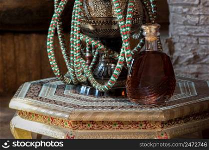 a bott≤of cognac and a hookah on a richly decorated antique decorative tab≤. a bott≤of alcoholic drink