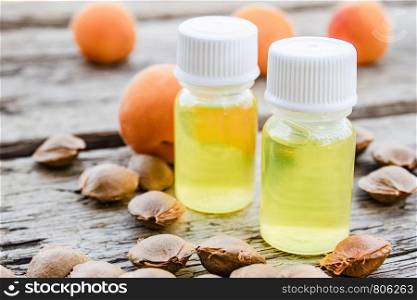 A bottle of apricot oil with apricot seeds and ripe apricots on a wooden table. Selective focus.. A bottle of apricot oil with apricot seeds and ripe apricots on a wooden table.
