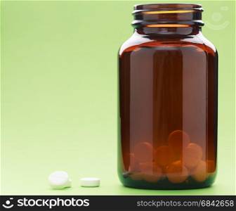 A bottle of brown-glass pills on a green background. A bottle of brown-glass drugs on a green background