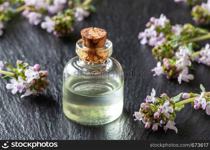 A bottle of essential oil with fresh blooming thyme