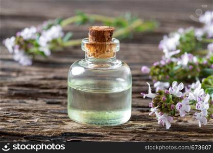 A bottle of essential oil with fresh blooming thyme on a rustic background