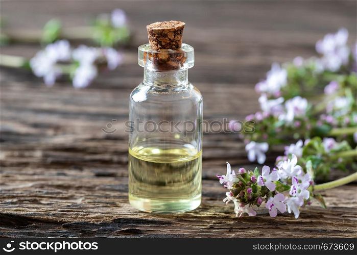 A bottle of essential oil with fresh blooming thyme twigs