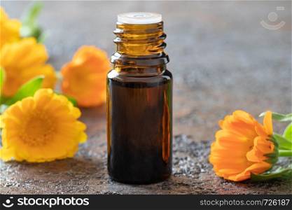 A bottle of essential oil with fresh calendula flowers