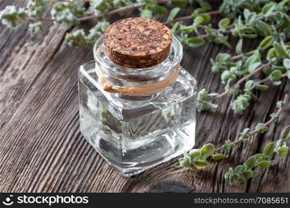 A bottle of essential oil with fresh marjoram twigs