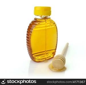 a bottle of honey and a wooden honey dipper on white background