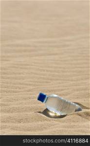 A bottle of mineral water in the sand of a bone dry desert