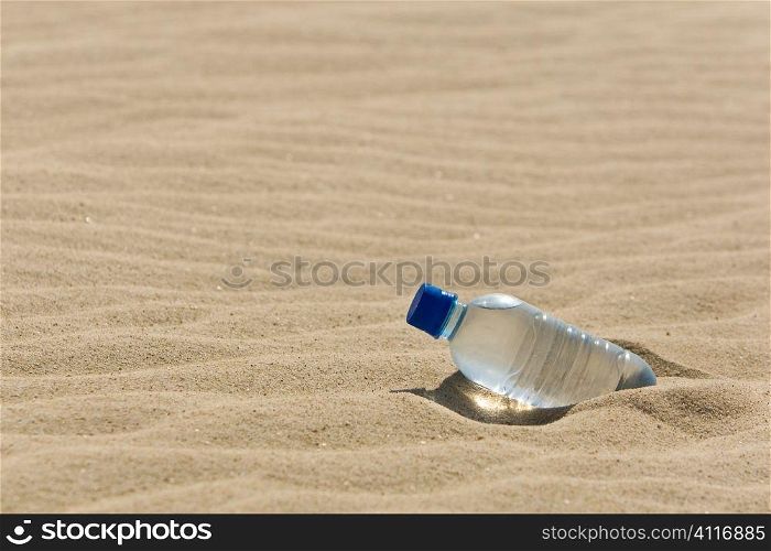 A bottle of mineral water in the sand of a bone dry desert