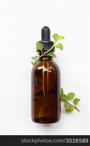 A bottle of oregano essential oil with fresh oregano leaves on w. A bottle of oregano essential oil with fresh oregano leaves on white background.