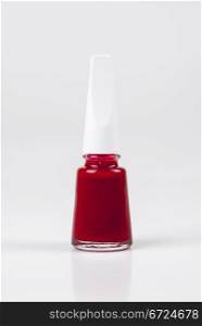 a bottle of red nail polish on white background