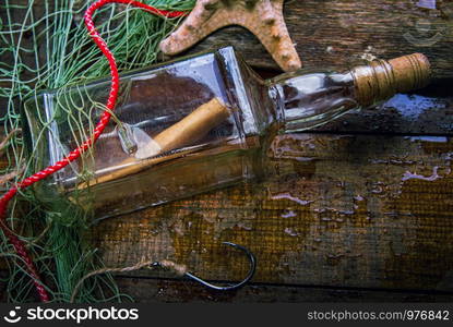 a bottle of shipwreck lies caught on an old wooden wet brown deck. fish net bacground