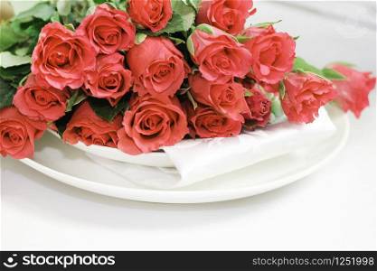 a bouquet of bright red roses on two plates on the table. space for text.
