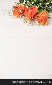 A bouquet of orange roses and gypsophila on wooden table. Copy space